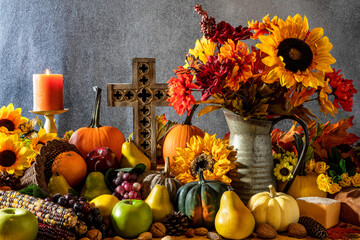 Naklejka na ściany i meble Thanksgiving cornucopia overflowing with fruit nuts pumpkins burning candle and wooden cross