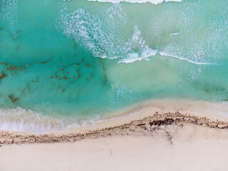 Sand beach. White sand. Sea water and waves. Turquoise water color. Drone shooting. Abstraction. Texture. There are no people in the photo. Minimalism. Rest, relaxation, sea travel.