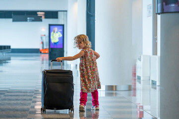 Cute blonde girl with travel luggage at the airport.