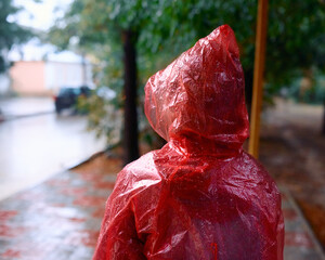 Woman in the rain in a raincoat at a bus stop
