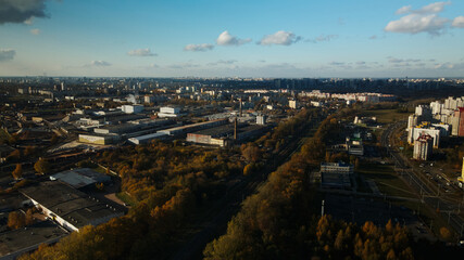 Obraz premium Flight over the autumn park. Trees with yellow autumn leaves are visible. On the horizon there is a blue sky and city houses. The park river is visible. Aerial photography.