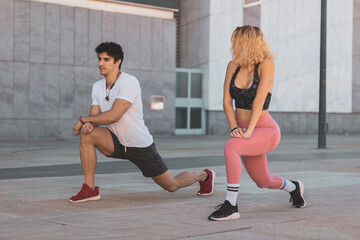 a young couple stretching in the middle of the street before exercising. 