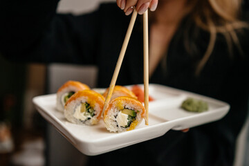 Girl eating sushi and rolls with chopsticks