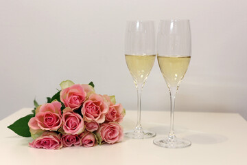 Two glasses of champagne and a bouquet of pink roses.