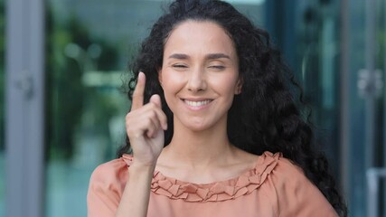 Female portrait hispanic woman curly pensive girl ethnic model lady deep in thought thinks makes decision pondering plan comes up with idea making gesture with forefinger shows direction to camera