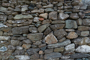 Stone wall made with rocks without concrete. Unique structure can be used as a background.
