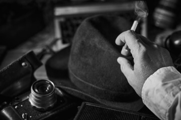Old vintage cinematic noir scene, detective's desk with a hat, telephone, camera, portable cassette...
