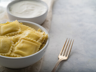 Close-up - ravioli, sour cream sauce. fork on a white background. Italian food. Culinary blog, cookbook, advertisement, restaurant, cafe, hotel.