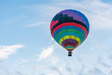 Multicolored hot air balloon on blue cloudy sky background