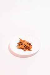 Split cinnamon for cooking stacked on white background. Pile of cinnamon on small plate.