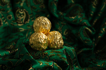 Tasty Chocolate Praline Wrapped with Golden Foil on Gorgeous Green Backdrop