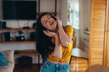 Woman dancing while listening a music on a headphones at home