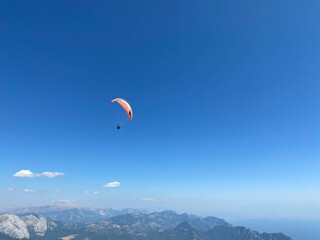 The parachutist flying high in the blue sky on a colorful parachute