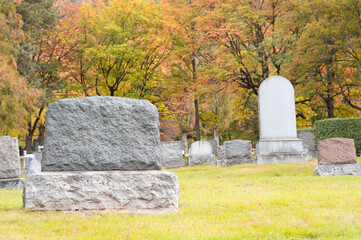 Old blank tombstones in cemetery on fall day.