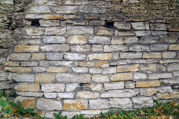 old stone wall of yellow brick with holes