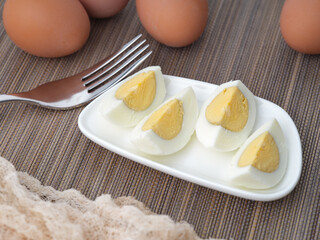 Sliced up hard boiled eggs on a small plate with a fork near them