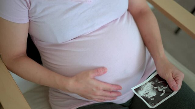 pregnant women holding ultra sound photo of her baby