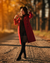 Beautiful , positive female in red coat during colourful autumn sunrise