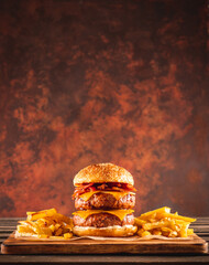 Double beef and bacon burger with cheddar cheese and chips on a wooden board on a table, ready to eat. Size XL.