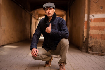 A man in a coat and cap walks around the city.