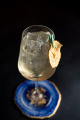Close up of transparent gin and tonic cocktail in a goblet, ice cubes sparkling beautifully on light