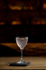 Small aperitif cocktail in blurred lights of dark empty bar