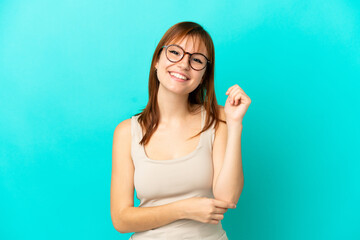 Redhead girl isolated on blue background laughing