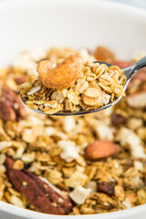 Cashews and granola on a spoon close-up. Nut granola macro