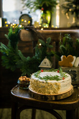 Christmas cake with white cream on a wooden chair. Pastries for the holiday and a Christmas wreath against the background of sparkling garland