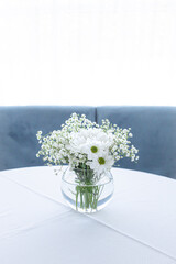Fototapeta premium Round glass vase. White flowers. Light room. White color in the interior. Wedding decorations. Bright kitchen. Cozy place. Romantic bouquet. Cozy white kitchen. A room flooded with light.
