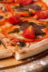 Slice of pizza with paprika, meat and tomatoes on the wooden board horizontal frame