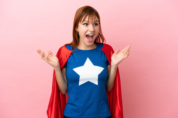 Super Hero redhead girl isolated on pink background with surprise facial expression