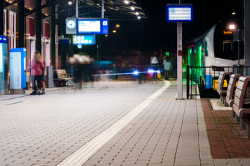 Train station with moving people getting on and off the train on arrival and departure platform