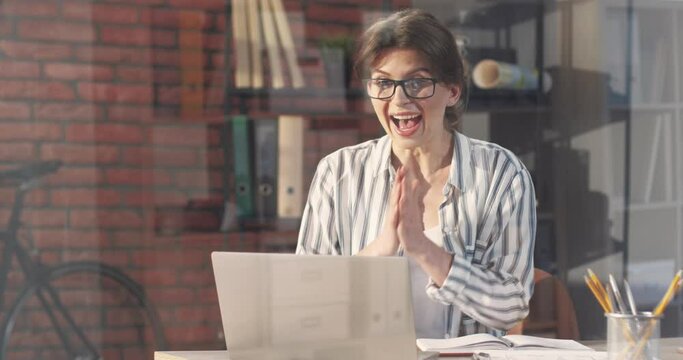 Young beautiful business woman working intently in office on laptop and looking forward to receiving email with good news.