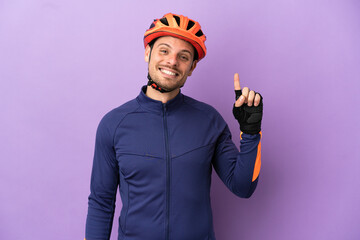 Young Brazilian cyclist man isolated on purple background pointing up a great idea - obrazy, fototapety, plakaty