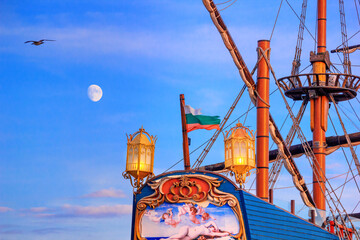 Fototapeta premium View of the stern of a stylized vintage sailboat against the background of the evening sky in the port of Varna, on the Black Sea coast of Bulgaria