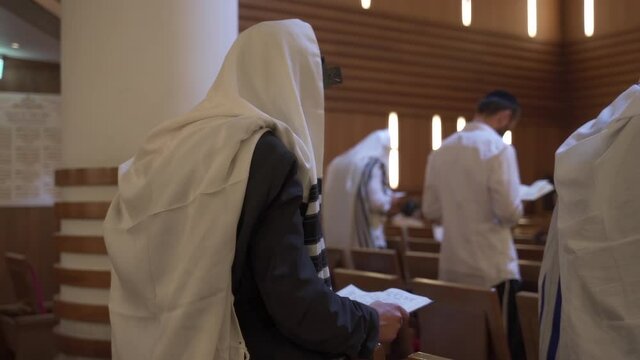 A group of people, Jews, pray in the synagogue. Rearview.