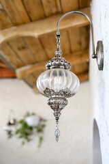 one oriental-style lamp made of glass hand carved metal with a wall mount above the entrance to the house from the outside, without light