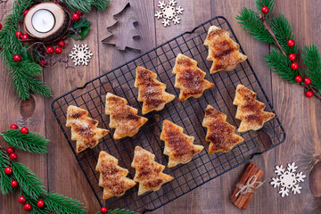 Christmas tree shaped puff pastry cookies with sugar and cinnamon on a cooling rack - obrazy, fototapety, plakaty