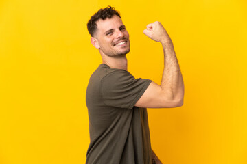 Young caucasian handsome man isolated on yellow background doing strong gesture