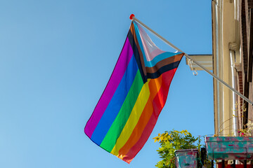 Progress pride flag (new design of rainbow flag) waving in the air with blue sky, Celebration of...
