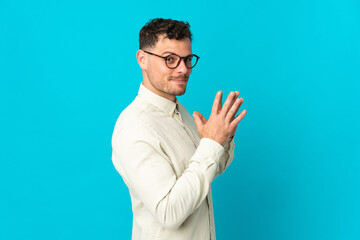Young caucasian handsome man isolated on blue background scheming something