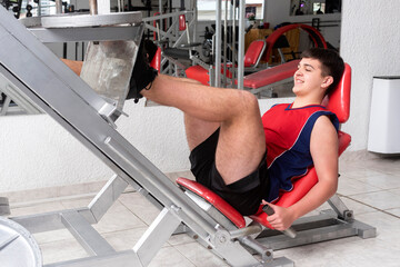 young muscular man doing physical activity in a gym, with machines and weights for a healthy life