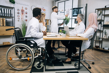 Group of multiracial medical workers discussing gene modification while sitting together at bright office. Qualified doctors researching dna peculiarities during international conference.
