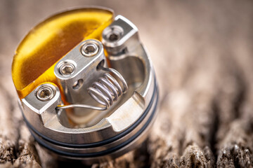 close up shot of space coil with ultem single coil reducer in high end rebuildable dripping atomizer for flavour chaser on rustic natural wood texture background, vaping device