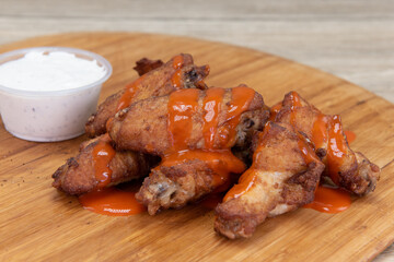 Side dish of drizzled buffalo chicken wings are the perfect appetizer for a hearty meal to eat