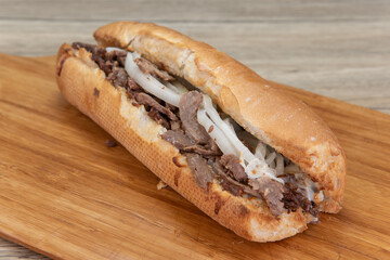 Enormously long philly cheesesteak sandwich loaded with meat and onions lying on a platter ready to eat