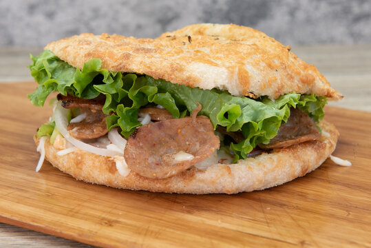 Freshly baked panuozzo pizza sandwich with all the toppings inside served on a wooden platter