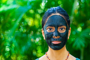 Happy woman with charcoal facemask 
