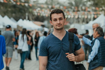 Handsome looking guy, international student male looking at the camera with a backpack and crowd people background 